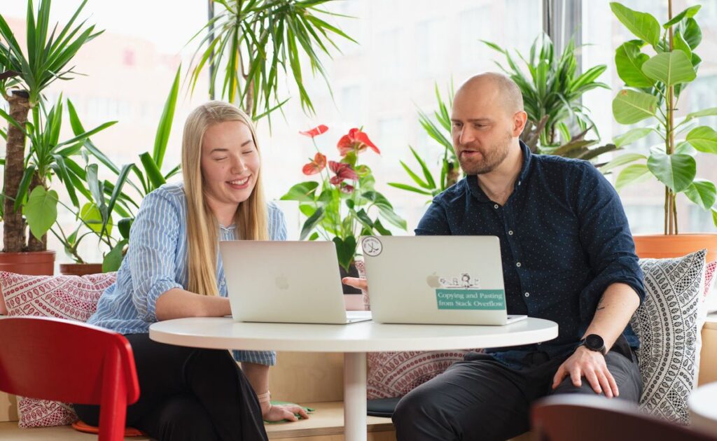 kaksi ihmistä kannettavien tietokoneiden ääressä